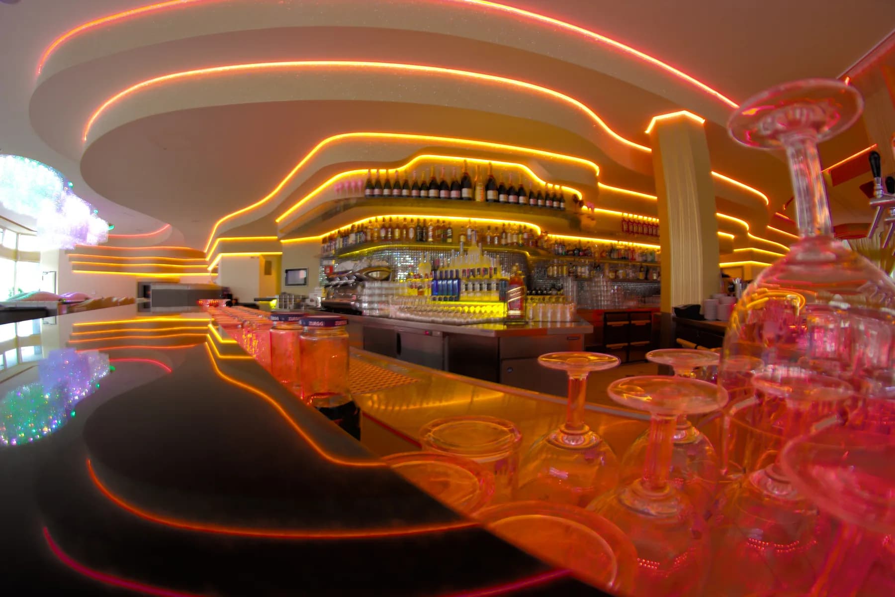 Bar des MIO Berlin bei Nacht mit leuchtender Theke und Gläsern im Vordergrund